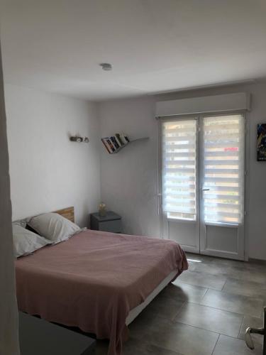 een slaapkamer met een bed en 2 ramen met jaloezieën bij appartement en rez de villa in Gattières