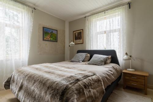 Newly renovated Latvian farm house في Kraujas: غرفة نوم بسرير كبير مع نافذتين