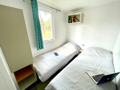 - une petite chambre avec un lit et un ordinateur portable dans l'établissement Spacieux Mobilhome Premium/Camping 5*, à Vendays-Montalivet