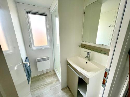 une salle de bain avec un lavabo, un miroir et une fenêtre dans l'établissement Spacieux Mobilhome Premium/Camping 5*, à Vendays-Montalivet