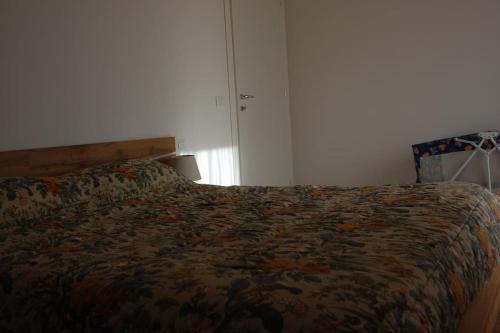 a bedroom with a bed with a floral blanket at LA CIESA DEI SIORI in Alleghe