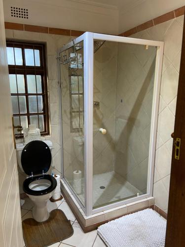 a bathroom with a shower with a black toilet at Waterloo Guest House in Durban