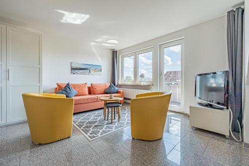 a living room with a couch and chairs and a tv at Appartementhaus Gouverneur-Maxse Büsum in Büsum