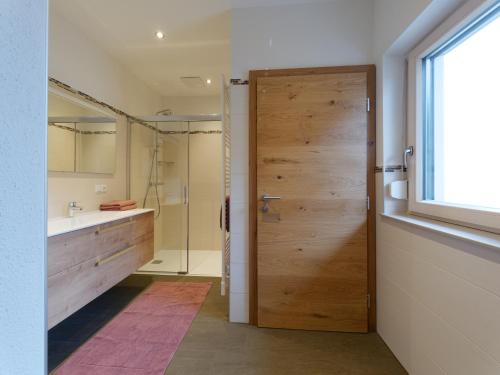 uma casa de banho com uma porta de madeira e um lavatório em Urlaub am Obsthof Pieber em Weiz