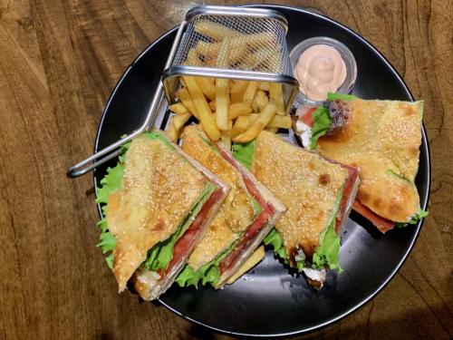 a black plate with a sandwich and french fries at Hotel Keto in Podgorica