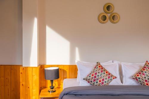 a bedroom with a bed with pillows and a clock on the wall at Zostel Manali, Vashisht in Vashisht