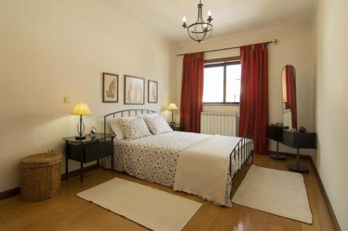 a bedroom with a bed and a window with red curtains at Santa Barbara Flat in Arcos de Valdevez