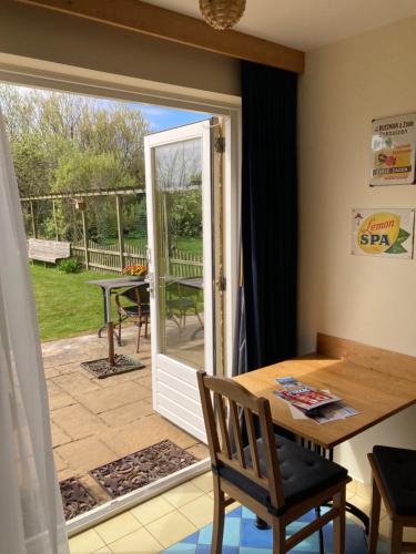 eine offene Tür zu einer Terrasse mit einem Tisch und Stühlen in der Unterkunft Carels Kamers Texel in De Koog