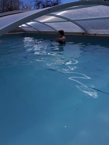 una persona en una piscina bajo un dosel en Chambre de caractere, en Celles
