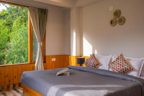 a bedroom with a bed and a large window at Zostel Manali, Vashisht in Vashisht