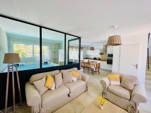 a living room with two couches and a kitchen at Les Jardins du Castelas - Domaine et Spas in Uchaux