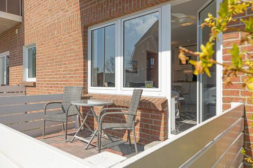 a patio with chairs and a table and a window at Appartementhaus Gouverneur-Maxse Büsum in Büsum
