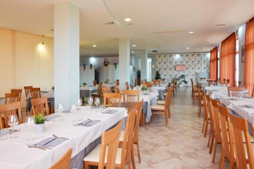 a dining room with white tables and wooden chairs at Hotel La Siesta in Torino di Sangro