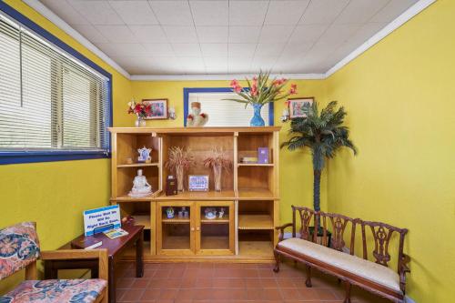 a waiting room with yellow walls and a table and chairs at OYO Hotel Luling TX Downtown I-10/US-90 in Luling