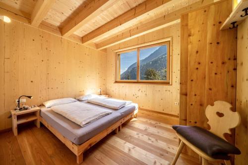 una camera da letto in una baita di tronchi con un letto e una finestra di Mayrhof Apartment Im Kirschgarten a San Pancrazio dʼUltimo