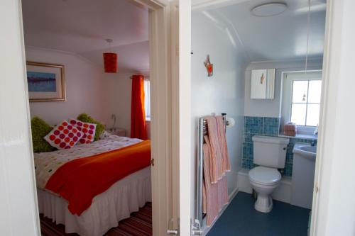 a bedroom with a bed and a toilet and a sink at Krissie's in Marazion