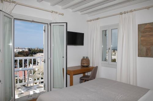 a bedroom with a bed and a desk and a balcony at Elena Hotel Mykonos in Mýkonos City