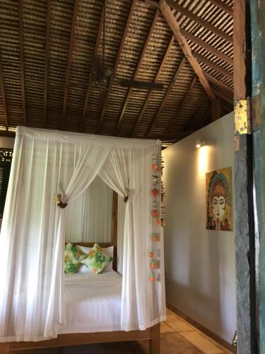 una cama con dosel en una habitación en Villa KAROUNA, en Sukawati