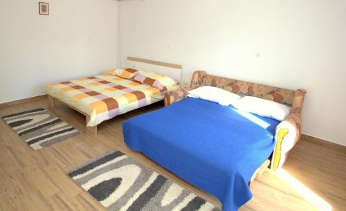 a bedroom with two beds and a rug at Apartmani Loli in Ugljan