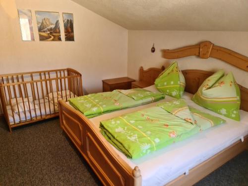 聖蘭布雷希特的住宿－Schöne Ferienwohnung im Naturpark Grebenzen，一间卧室配有一张带绿床单的床和一张婴儿床。