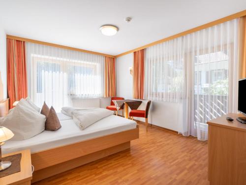 a hotel room with a bed and a desk and windows at Apartment Rosa-6 by Interhome in Mayrhofen