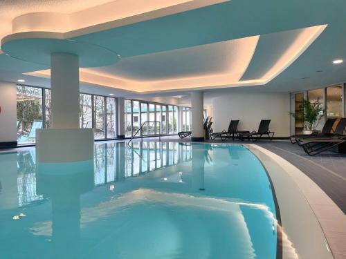 a large swimming pool in a hotel lobby with a swimming poolvisorvisor at Dorint Sanssouci Berlin/Potsdam in Potsdam