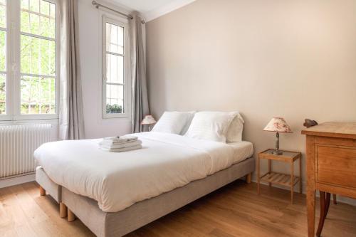 une chambre blanche avec un grand lit et deux fenêtres dans l'établissement Eiffel Tower Lourmel Residence, à Paris
