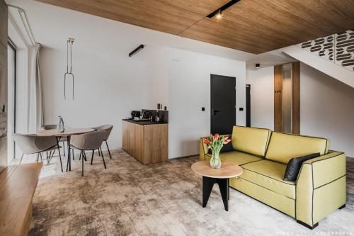 a living room with a yellow couch and a table at Tremonti Hotel Karpacz in Karpacz
