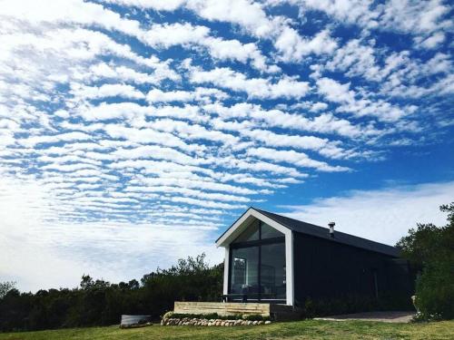 a black building with a window and a cloudy sky at Hillandale Hideaway in Plettenberg Bay