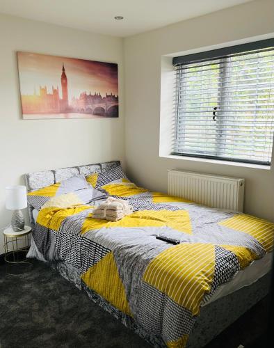 a bedroom with a bed with a yellow and gray blanket at Green Lantern, Private En-suite Double Bedroom in Aveley