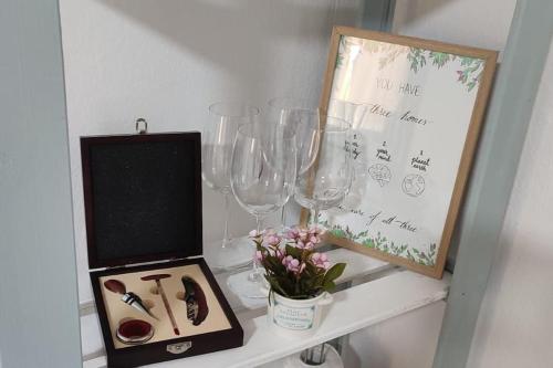 uma mesa com copos de vinho e uma caixa. em Well-located rural house on a spacious fenced lot em Novi Sad