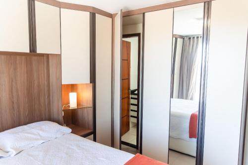 una camera da letto con un letto e uno specchio di Cf02 Cobertura 3 quartos 200m da Praia das Dunas a Cabo Frio