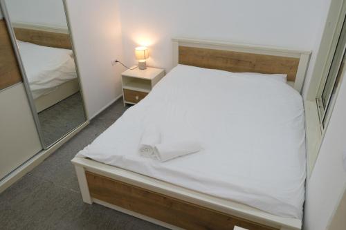 sypialnia z białym łóżkiem i lustrem w obiekcie Hermon Suites w mieście Madżdal Szams