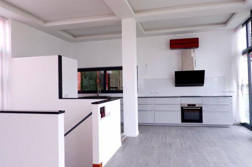 a kitchen with white cabinets and a tv at Swiss House 5 in Pattaya South