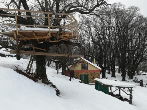a tree house in the snow next to a building at Hani Kastania - Chania retreat for families and groups for holidays and workshops in Sémbronas