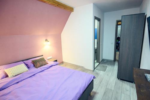 een slaapkamer met een paars bed met een roze muur bij Cabana Zabet in Ranca