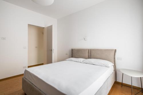 1 cama blanca en un dormitorio blanco con mesa en Santo Stefano Design Apartment by Wonderful Italy en Bolonia