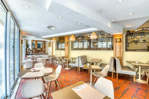 a restaurant with tables and chairs and windows at Mercure Avignon Centre Palais des Papes in Avignon