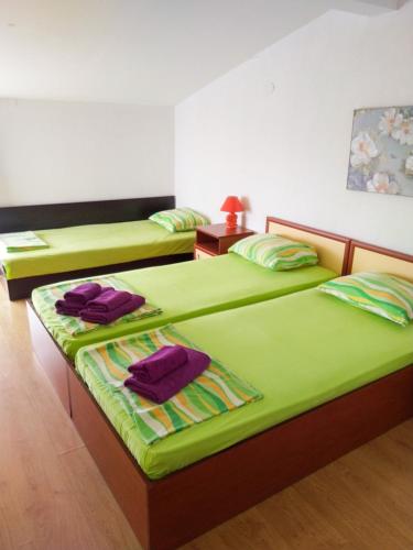 two beds in a room with green sheets and purple pillows at Kъща за гости Прохлада 3 и 4 етаж in Sinemorets