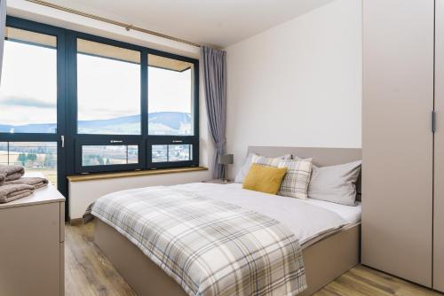 a bedroom with a large bed and large windows at Apartmán Simba Klínovec in Loučná pod Klínovcem