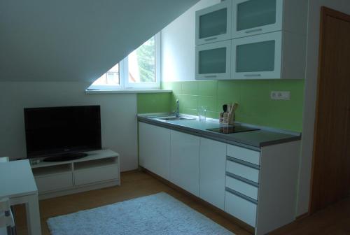 a kitchen with a sink and a flat screen tv at Penzion Emilia in Ružomberok