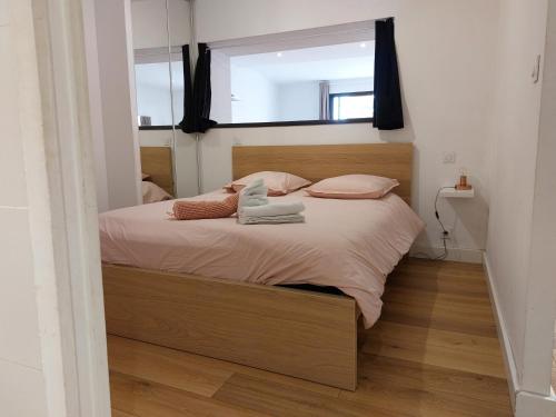um quarto com uma cama com almofadas cor-de-rosa e uma janela em Le DenysPuech 55m2 plein centre avec jardin! em Rodez