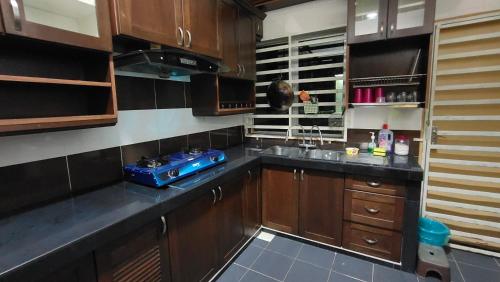 una cucina con armadi in legno e stufa blu di Sentosa2Stay Gong Badak Kuala Terengganu a Kampong Gong Badak