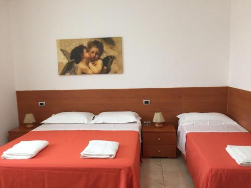 ポルト・チェザーレオにあるAppartamento Nadiaの赤いシーツと絵画が備わる客室内のベッド2台