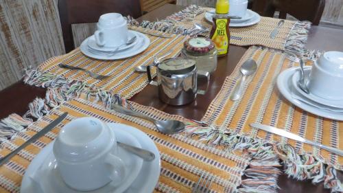 a table with plates and utensils on top of it at Pousada Manobra in Ubatuba