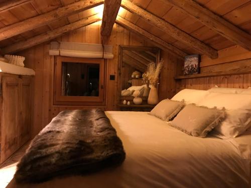 un grand lit dans une chambre aux murs en bois dans l'établissement Charmant Mazot Le 1881 4 pers, à Demi-Quartier