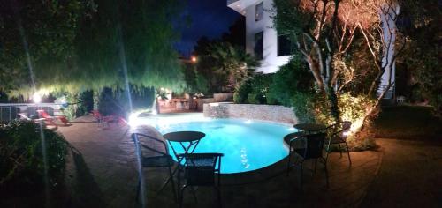 a swimming pool at night with chairs and a table at La Villa Saint Jean BAS DE VILLA in La Ciotat