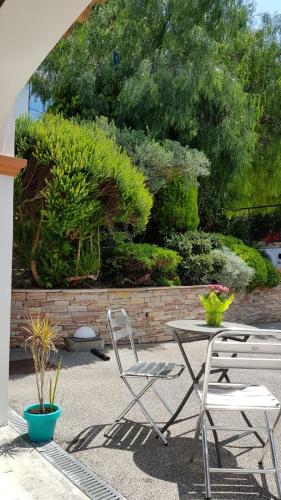 a patio with a table and chairs and bushes at La Villa Saint Jean BAS DE VILLA in La Ciotat