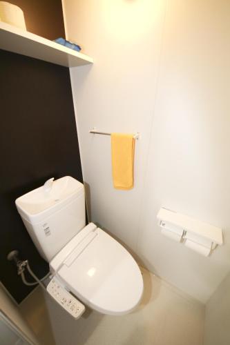 a bathroom with a white toilet and a yellow towel at Chura Gahna House Tsubogawa Naha in Naha