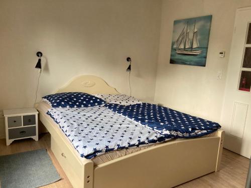 Schlafzimmer mit einem Bett mit einer blauen und weißen Bettdecke in der Unterkunft Ankerplatz in Böel für Sie, komplette Wohnung inkl. Terasse und Parkplatz 